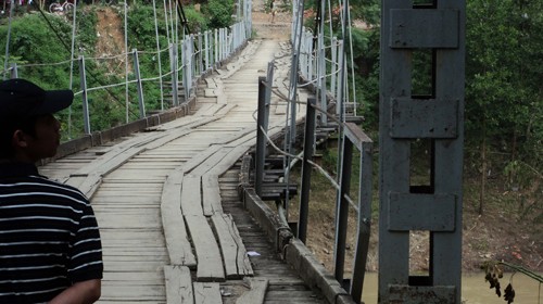 Nứt núi Pu Căm gây sạt đất khiến cây cầu treo bắc qua dòng Nậm Nơn (xã Lượng Minh, huyện Tương Dương) cong queo, gây nguy hiểm cho người và xe cộ qua lại - Ảnh: Nguyên An